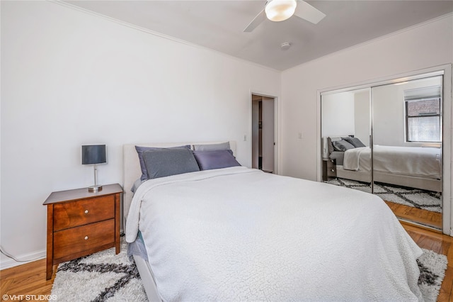 bedroom featuring crown molding, a ceiling fan, wood finished floors, and a closet