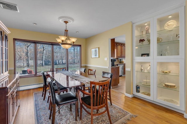 dining room featuring a notable chandelier, baseboard heating, baseboards, light wood-type flooring, and visible vents