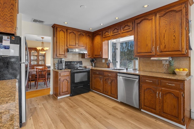 kitchen featuring visible vents, appliances with stainless steel finishes, a sink, light wood-style floors, and under cabinet range hood