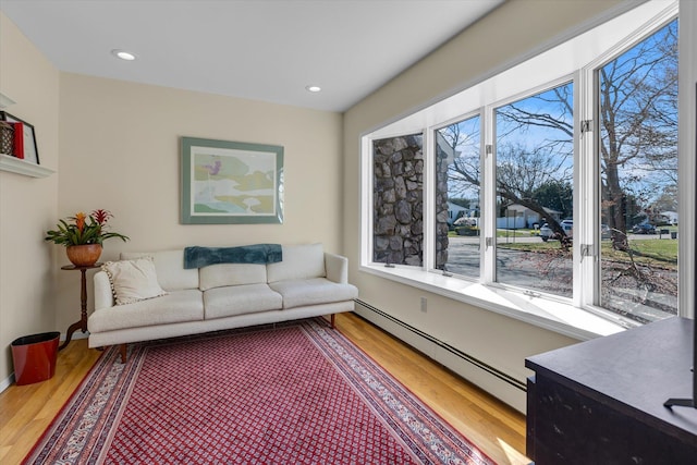 living area featuring light wood-style floors, a baseboard radiator, baseboards, and recessed lighting