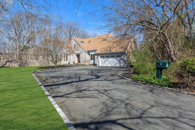 view of home's exterior with a chimney, a lawn, aphalt driveway, an attached garage, and stone siding