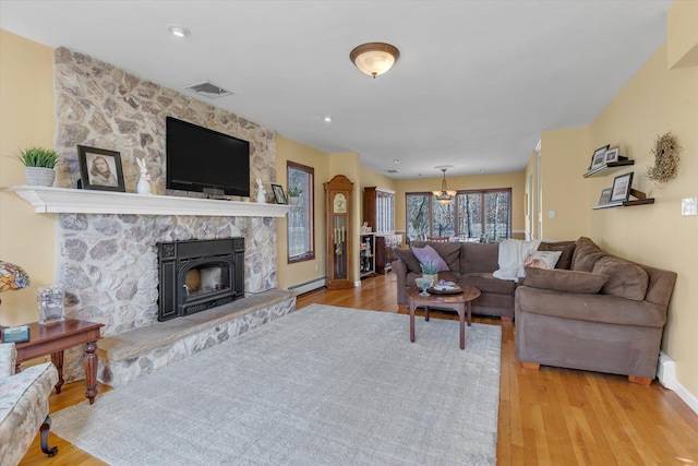 living area featuring visible vents, wood finished floors, a fireplace, baseboards, and a baseboard heating unit
