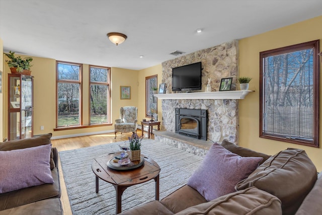 living room with a fireplace, wood finished floors, and visible vents