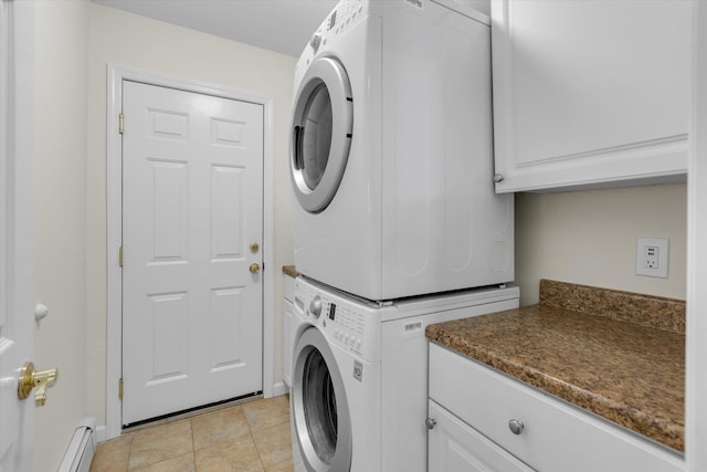 clothes washing area with baseboards, stacked washer and dryer, cabinet space, and a baseboard radiator
