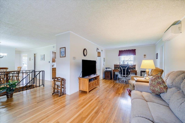 living room featuring crown molding, light wood-style floors, an AC wall unit, a textured ceiling, and a chandelier