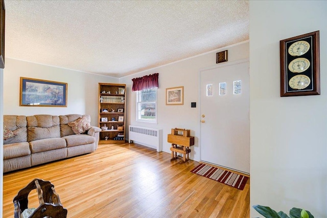 living area with wood finished floors, a textured ceiling, and radiator heating unit