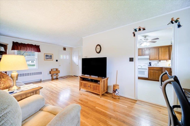 living room with crown molding, ceiling fan, light wood-style floors, a textured ceiling, and radiator heating unit