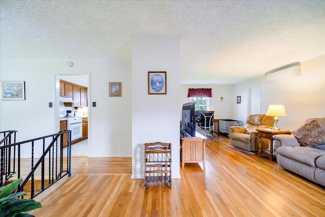 living area featuring a textured ceiling, light wood-type flooring, and a wall mounted air conditioner