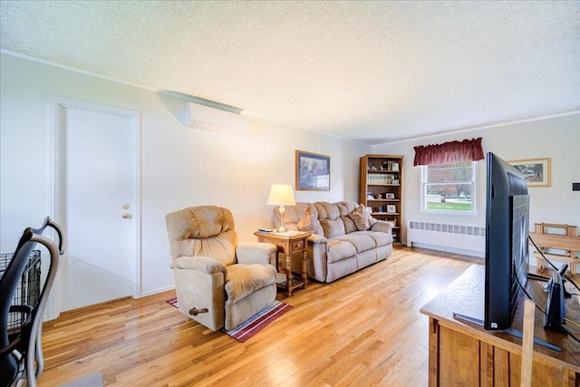 living area featuring an AC wall unit, a textured ceiling, radiator, and light wood-type flooring
