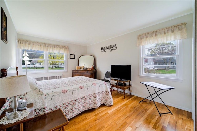 bedroom featuring crown molding, radiator, wood finished floors, and multiple windows