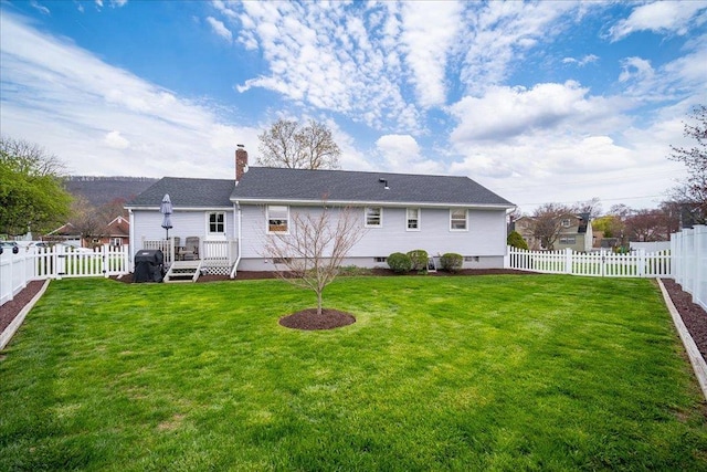 rear view of property featuring a yard, a chimney, and a fenced backyard