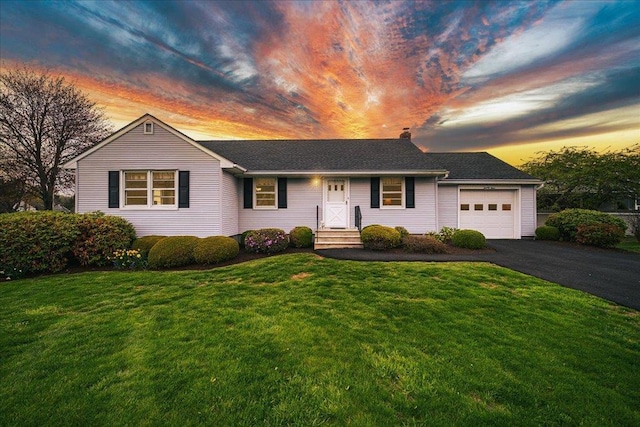 single story home featuring an attached garage, a yard, and aphalt driveway