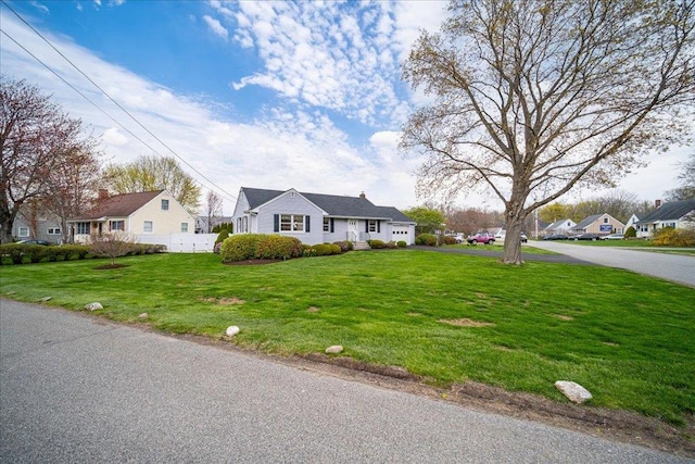 bungalow-style home featuring fence, driveway, a front yard, and a garage
