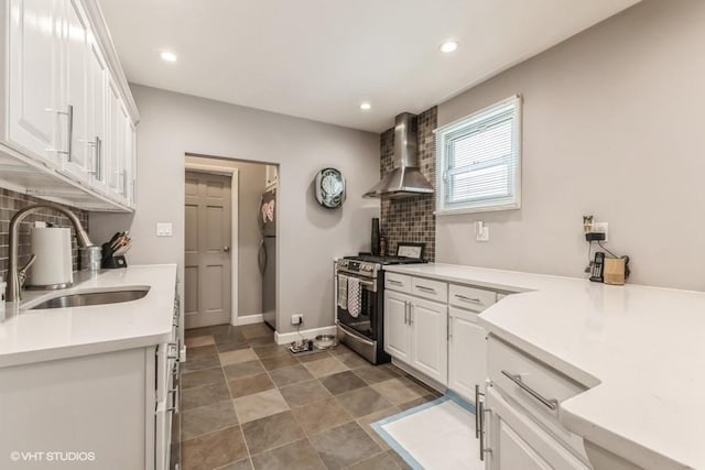 kitchen with tasteful backsplash, a sink, white cabinetry, stainless steel range with gas stovetop, and wall chimney exhaust hood