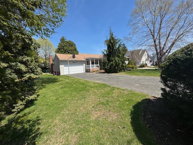 view of front of home featuring a garage, aphalt driveway, and a front yard