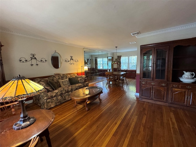 living area with visible vents, ornamental molding, and dark wood-type flooring