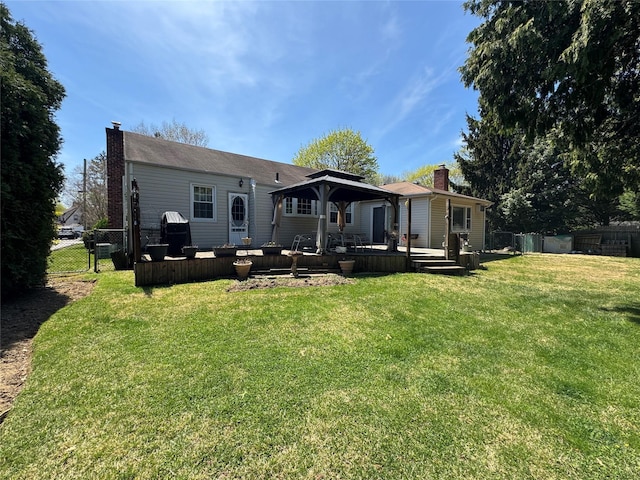 back of property featuring a gazebo, a fenced backyard, a lawn, and a chimney
