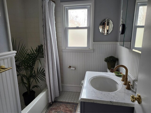 full bathroom featuring vanity, toilet, shower / bathtub combination with curtain, tile patterned floors, and a wainscoted wall