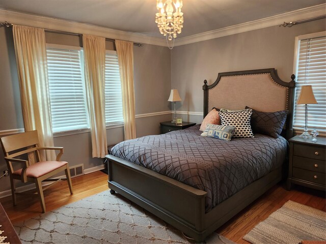 bedroom featuring baseboards, ornamental molding, multiple windows, and wood finished floors
