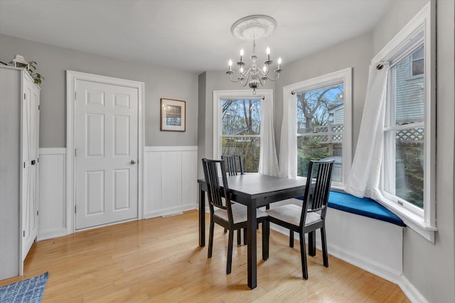 dining room with light wood-style floors, visible vents, wainscoting, and a notable chandelier