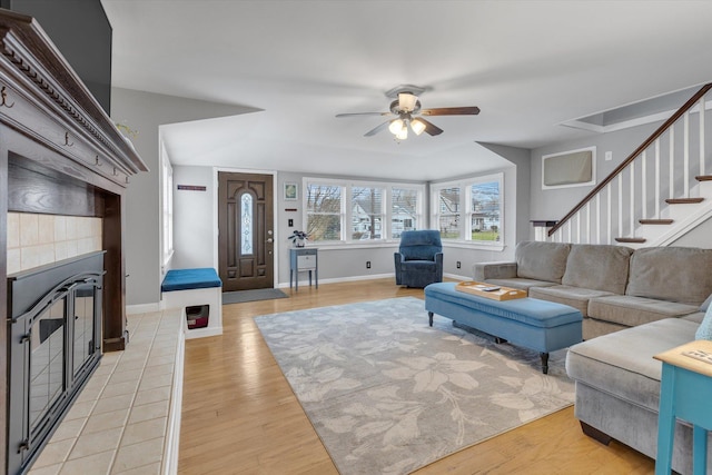 living room featuring baseboards, light wood finished floors, ceiling fan, and a fireplace