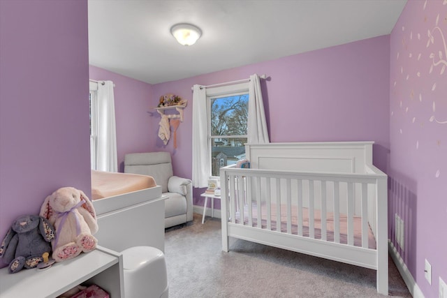 carpeted bedroom featuring baseboards and a crib