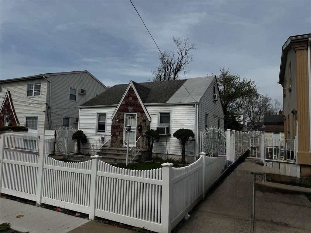 11922 237th St, Cambria Heights, NY 11411 - view of front facade featuring roof with shingles, a gate, and a fenced front yard