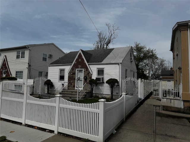 view of front facade featuring roof with shingles, a gate, and a fenced front yard