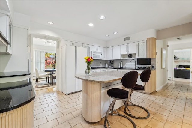 20 Rolling Ridge Rd, New City, NY 10956 - kitchen with white appliances, decorative backsplash, a breakfast bar, a center island, and light stone countertops