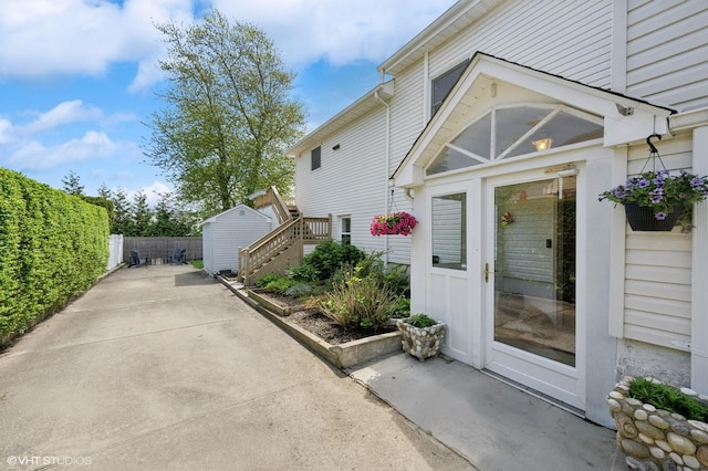 view of side of home with fence, a patio area, a storage shed, an outdoor structure, and stairs