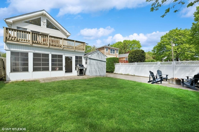 back of property featuring a fire pit, a balcony, an outdoor structure, a storage shed, and a patio area