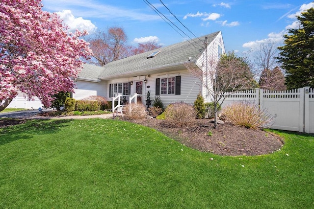 view of front facade with roof with shingles, fence, and a front yard