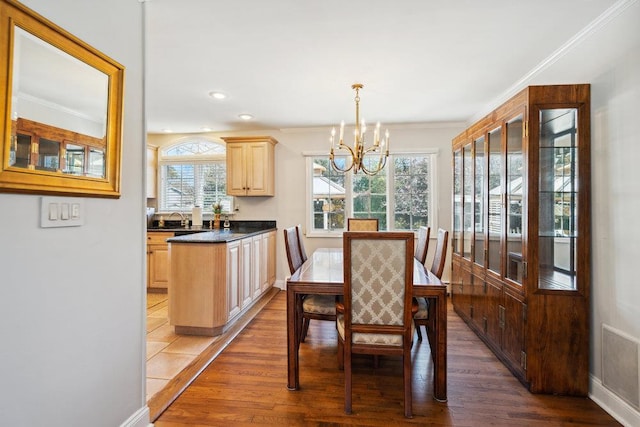 dining room featuring light wood-style floors, ornamental molding, and a notable chandelier