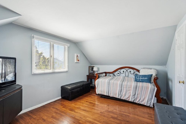 bedroom featuring baseboards, vaulted ceiling, and wood finished floors