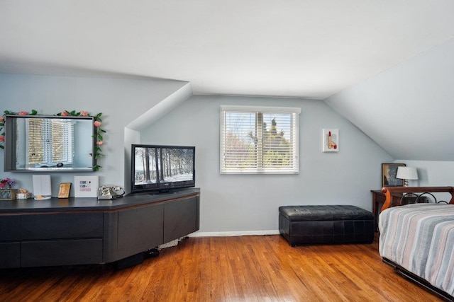 bedroom featuring baseboards, wood finished floors, and lofted ceiling
