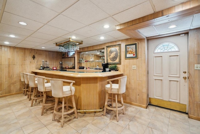 bar featuring baseboards, wood walls, and wet bar