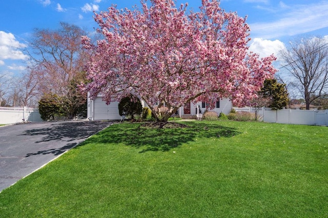 view of front of home featuring a front lawn, fence, and driveway