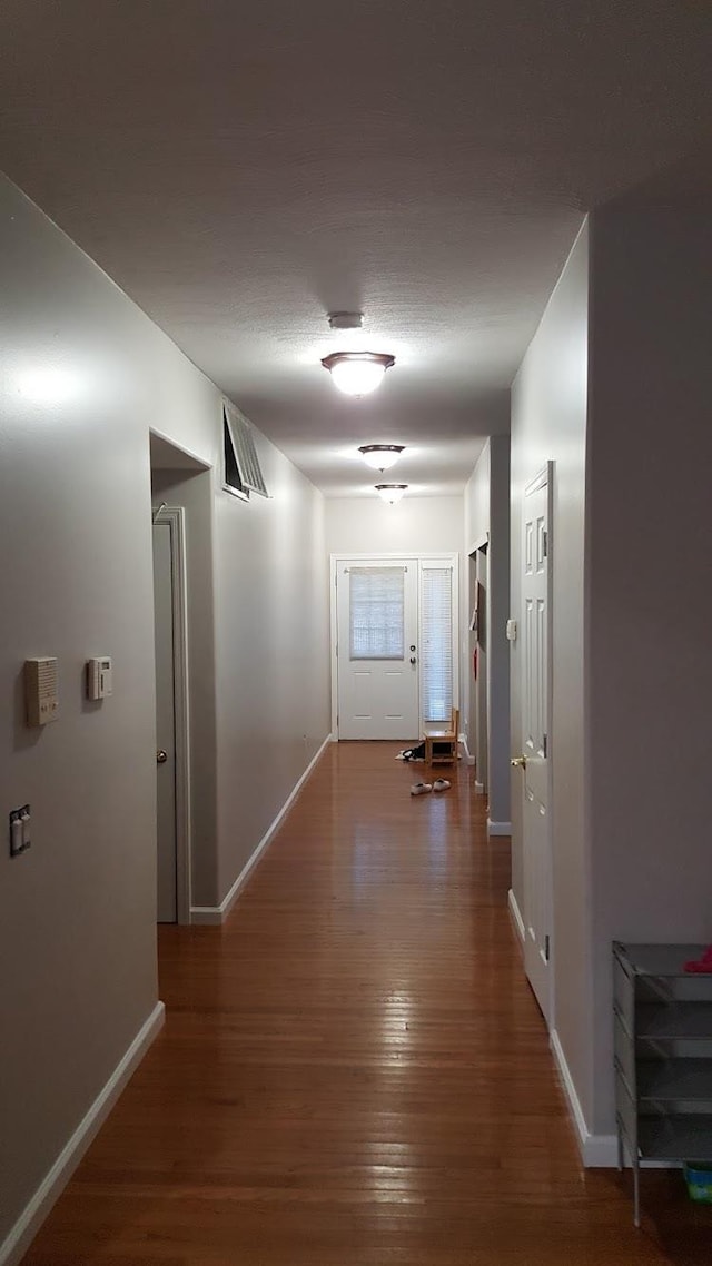 hall with baseboards and wood finished floors