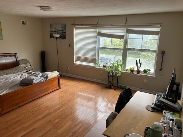 bedroom featuring visible vents, light wood finished floors, and multiple windows