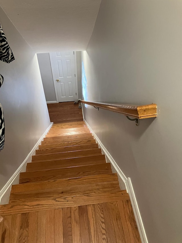 staircase featuring baseboards and wood finished floors