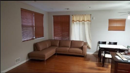living room with visible vents, baseboards, ceiling fan, and wood finished floors