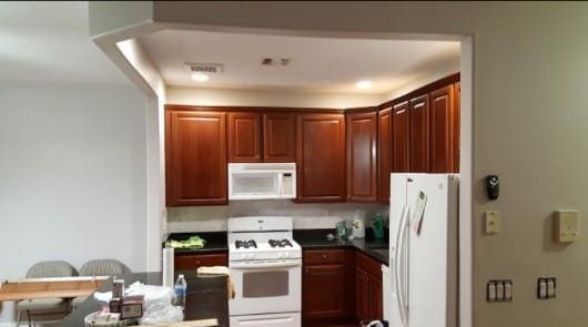 kitchen with white appliances and dark countertops