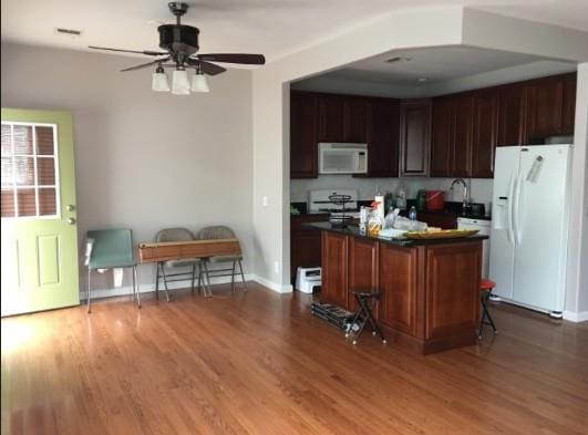 kitchen featuring dark countertops, a ceiling fan, white appliances, and wood finished floors