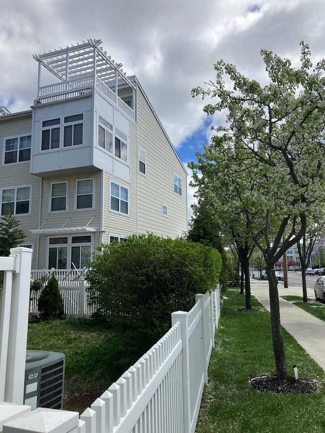 view of side of property with a lawn, cooling unit, and fence private yard