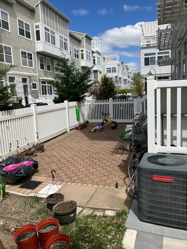 view of patio with a residential view, fence, and central AC unit