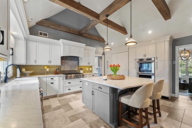 kitchen with recessed lighting, white cabinetry, appliances with stainless steel finishes, a kitchen island, and stone tile floors