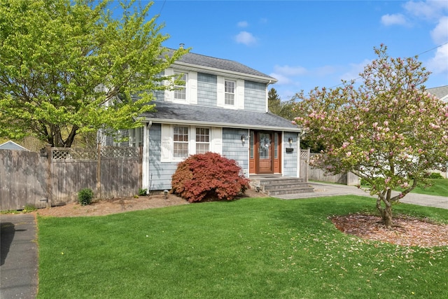 traditional-style home with fence, a shingled roof, and a front yard