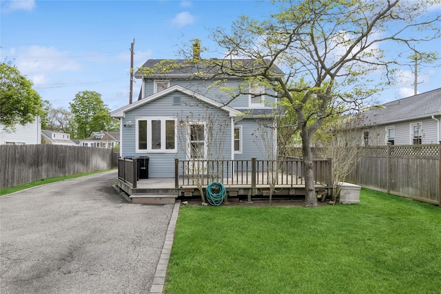 view of front of home featuring a wooden deck, a fenced backyard, and a front yard