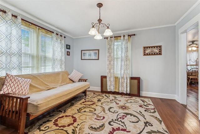 living area with crown molding, baseboards, a notable chandelier, and hardwood / wood-style flooring