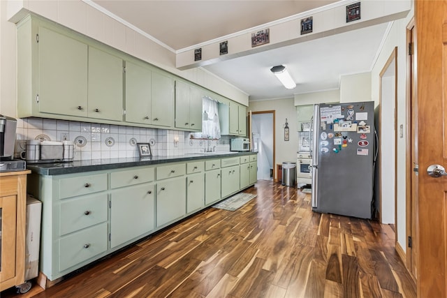 kitchen with crown molding, green cabinetry, freestanding refrigerator, and white microwave